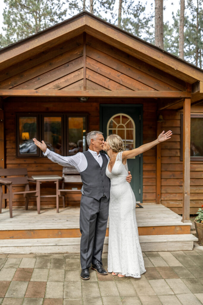 The bride and groom photographed by the Brainerd wedding photographer in front of their lakeside cabin